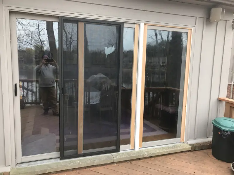 Sliding patio door with new wood trim installed along the frame