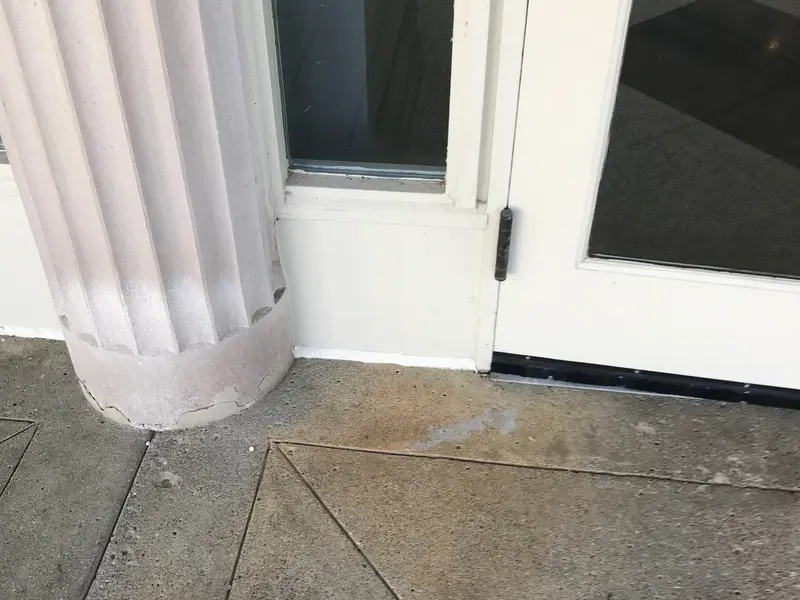 Exterior door next to a white column on a concrete porch