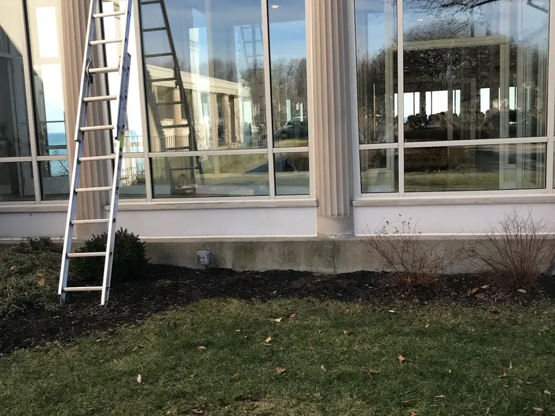 Large commercial windows with a ladder leaning against the building