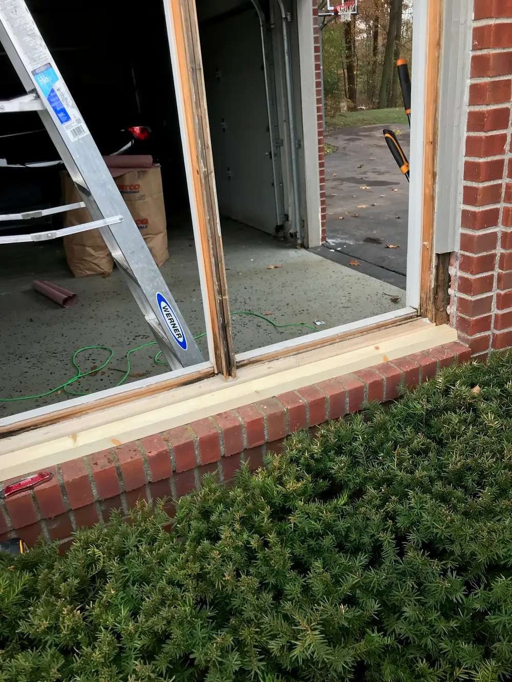 Window opening in a brick wall with the glass removed and a ladder inside