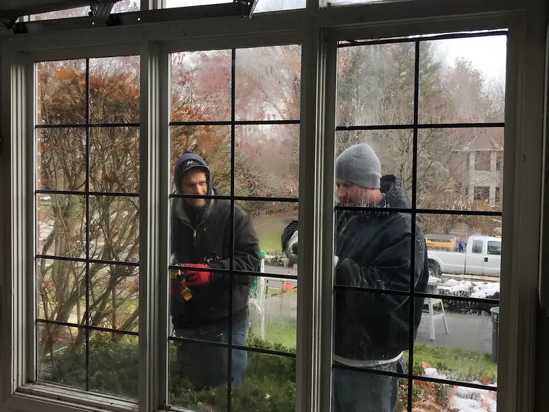 Crew working on a large arched window, seen from inside the home