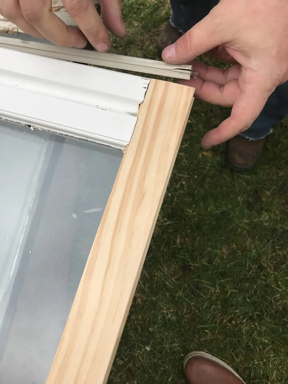 Hands fitting a new wood strip onto a window sash